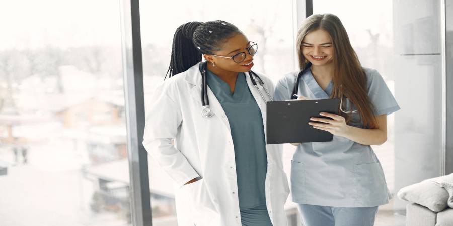 Home Two female healthcare professionals discussing documents in a bright medical setting.